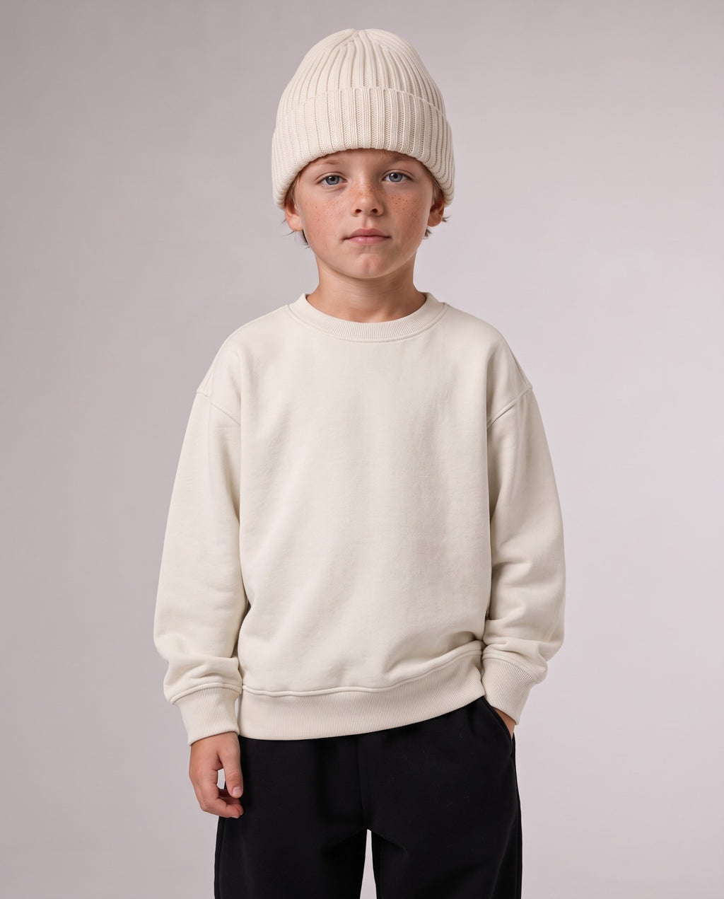 BELOUD Kids Beanie aus Bio-Baumwolle in Almond – getragen, Halfbody mit Ivory-Sweater und schwarzer Jogginghose
