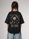 Mädchen von hinten im schwarzen BIG MOOD Oversize Shirt von BELOUD mit beigem Grunge-Smiley-Backprint