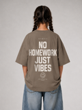 Mädchen von hinten im driftwoodfarbenen NO HOMEWORK JUST VIBES Oversize Shirt von BELOUD mit cremefarbenem Statement-Backprint
