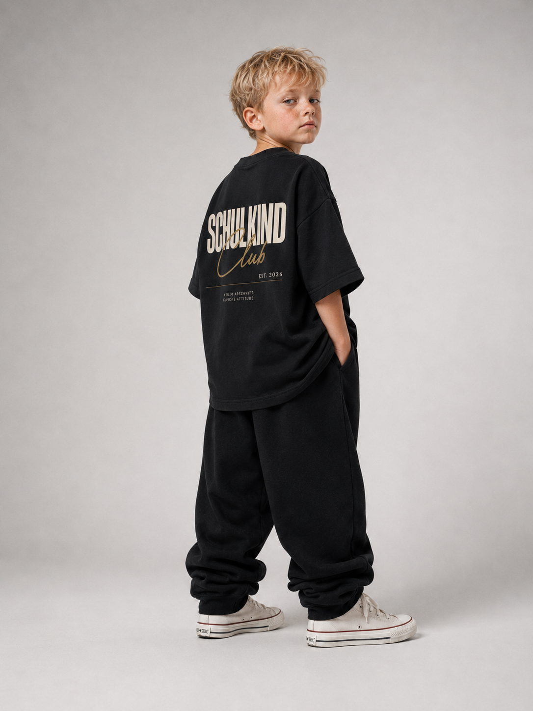 Junge im schwarzen SCHULKIND CLUB Oversize Shirt von BELOUD mit beige-goldenem Backprint