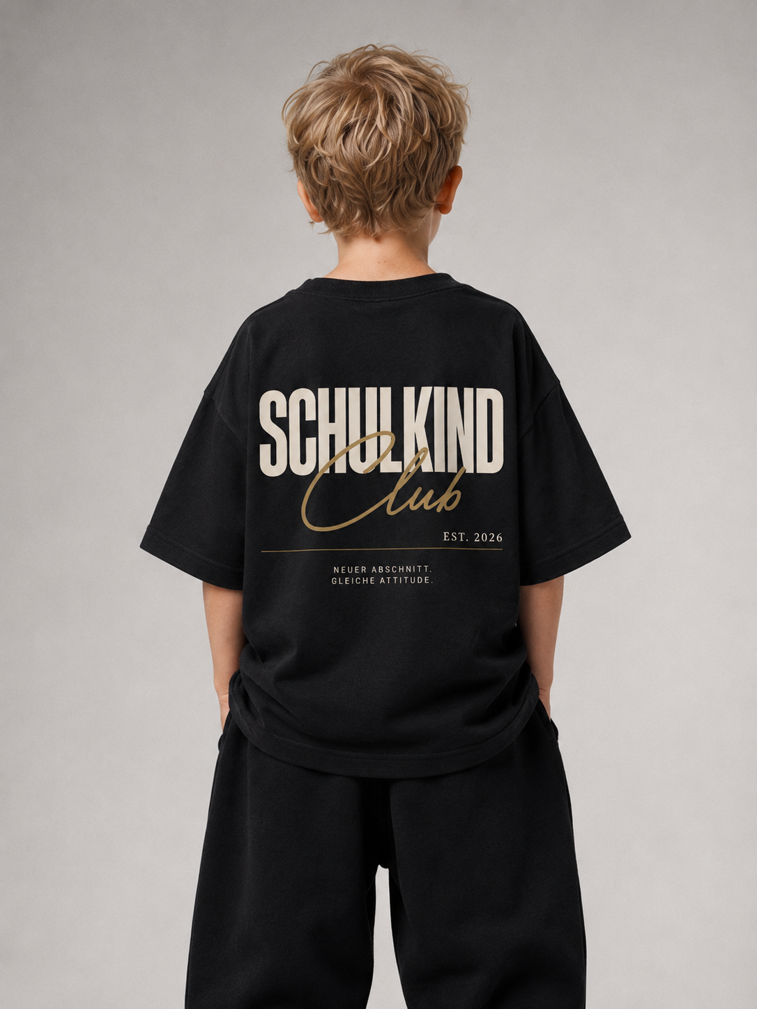 Junge von hinten im schwarzen SCHULKIND CLUB Oversize Shirt von BELOUD mit beige-goldenem Backprint