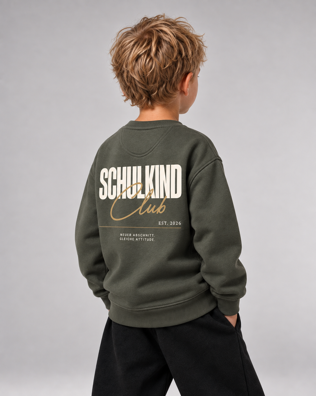 Junge trägt SCHULKIND CLUB 2026 Kids Sweater in Organic Khaki – Dreiviertel-Rückansicht