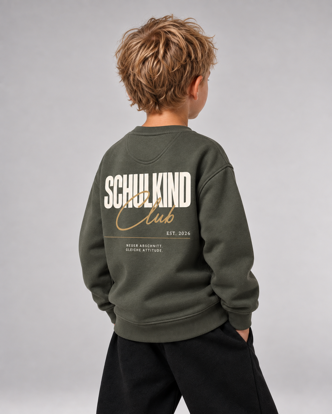 Junge trägt SCHULKIND CLUB 2026 Kids Sweater in Organic Khaki – Dreiviertel-Rückansicht