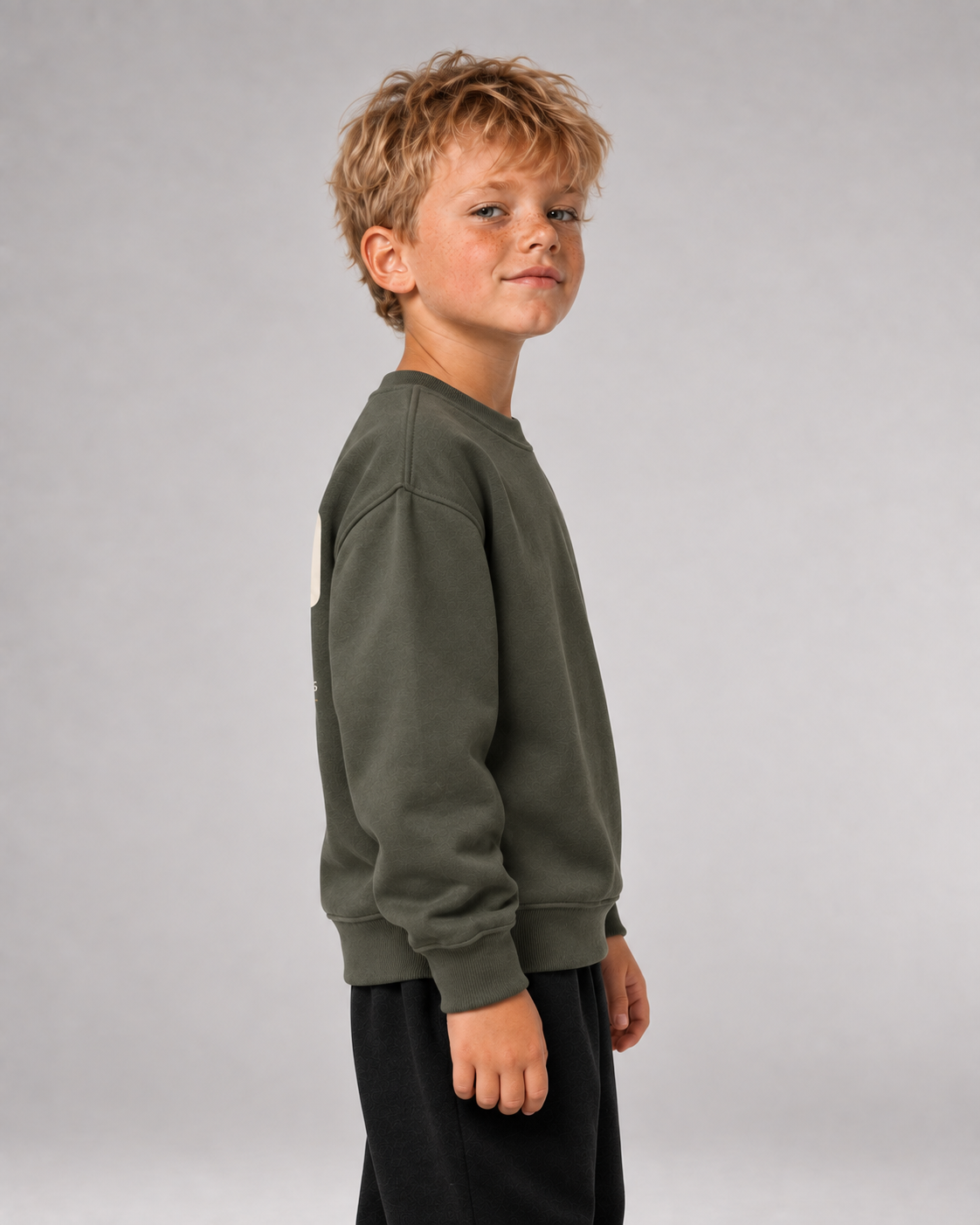 Junge trägt SCHULKIND CLUB 2026 Kids Sweater in Organic Khaki – Seitenansicht