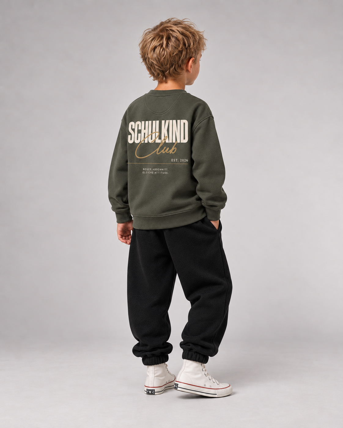 Junge trägt SCHULKIND CLUB 2026 Kids Sweater in Organic Khaki – Ganzkörper Dreiviertel-Rückansicht