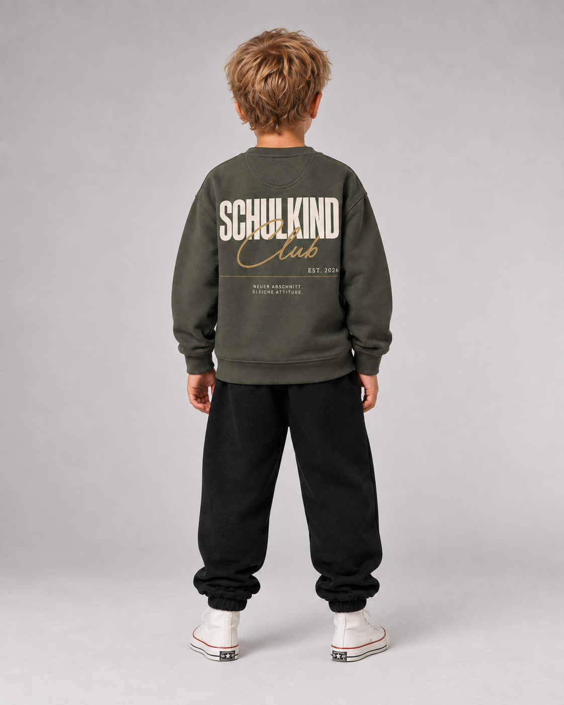 Junge trägt SCHULKIND CLUB 2026 Kids Sweater in Organic Khaki – Ganzkörper Rückansicht